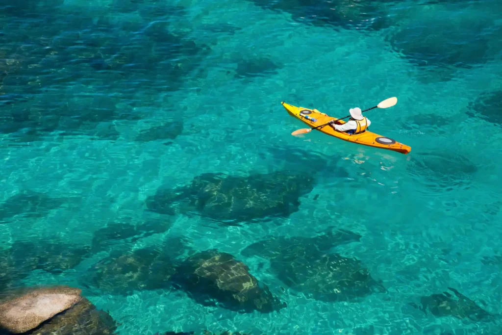 Man in a yellow kayak paddling on the turquoise waters of Lake Tahoe 