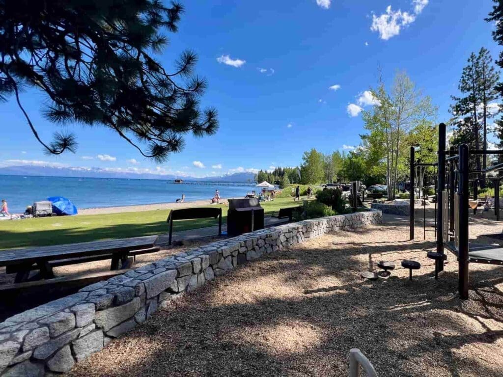 A picture of Commons Beach in Tahoe City, with the playground, grassy park and beach in the background