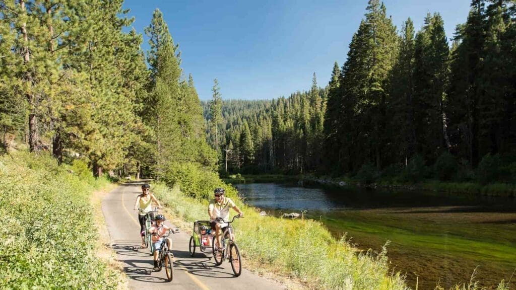 Family biking on the Truckee River Bike Trail with the river flowing next to them