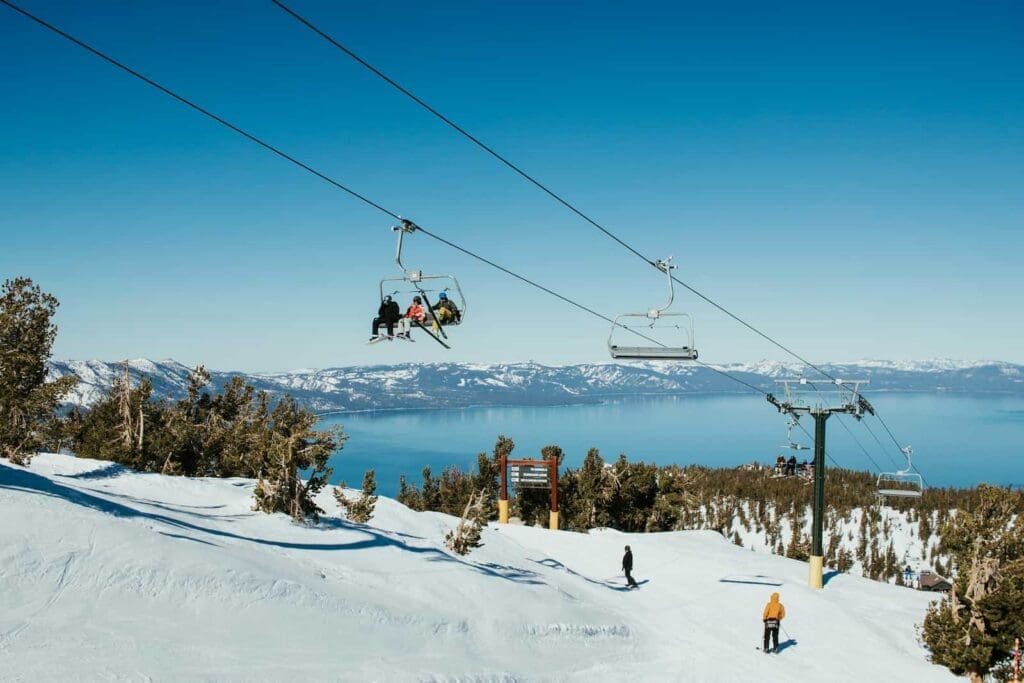 Skiers riding the Heavenly Mountain ski lift with Lake Tahoe in the background